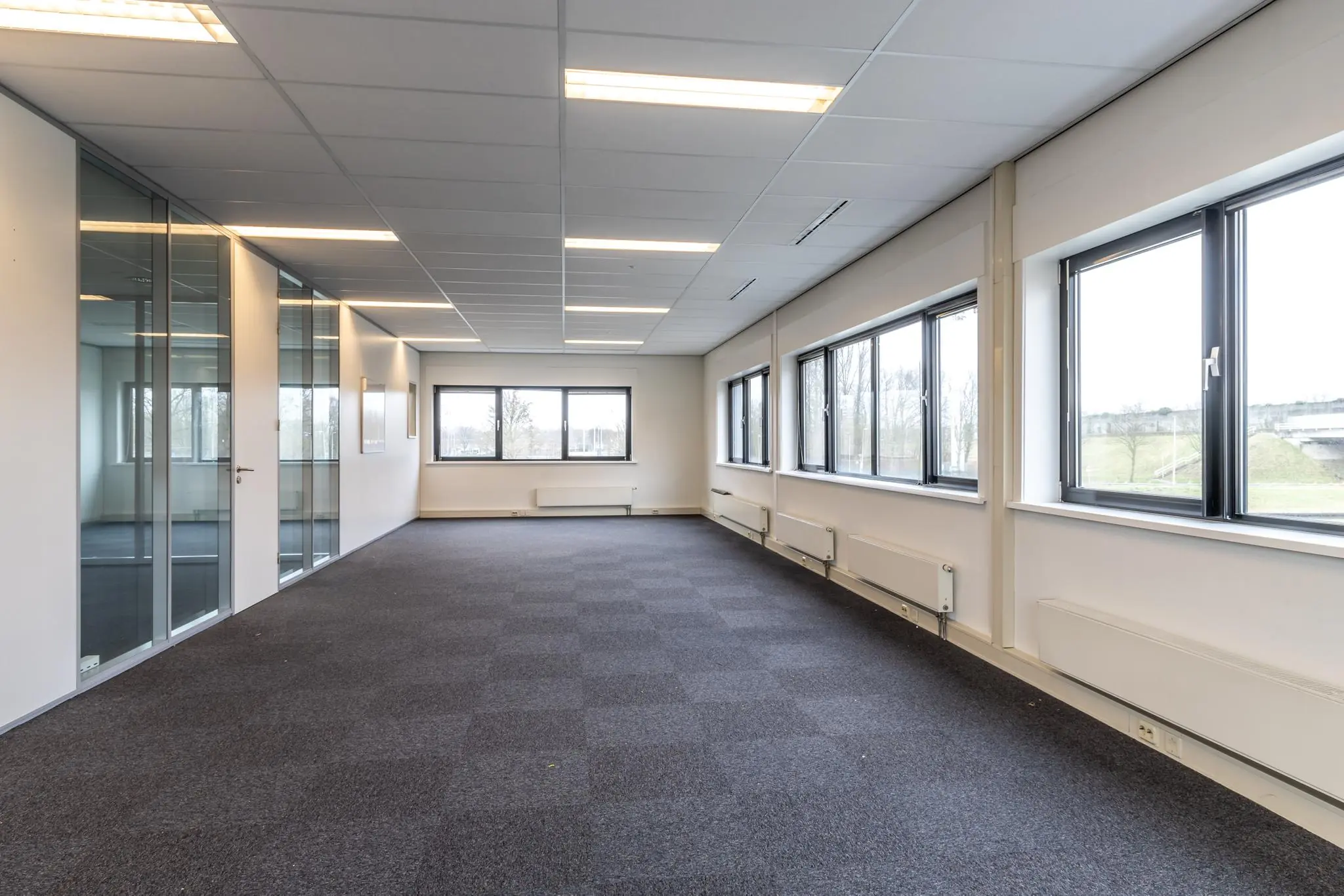 Licht en ruim kantoorinterieur aan de Lage Biezenweg met grote ramen en glazen scheidingswanden.